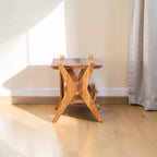 Homecrest acacia wood Corbel side table with a natural grain finish and unique X-frame design in a bright room.