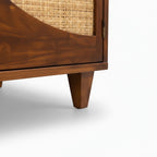 Close-up of the tapered wooden leg and honey-toned frame of the Homecrest Aldon media unit with cane webbing detail.