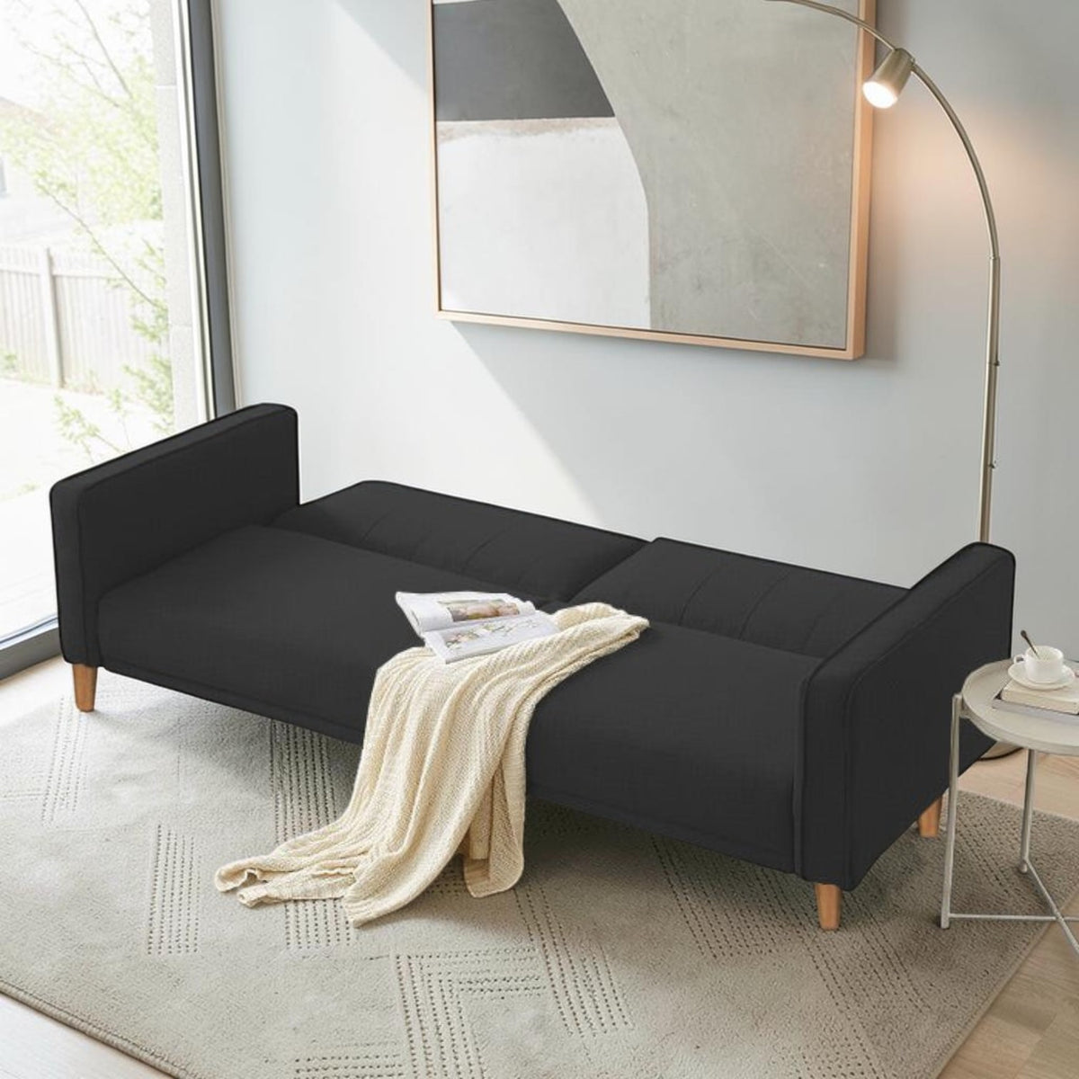 Homecrest Aldous black polyester three-seater sofa bed with solid wood legs in a modern living room setting
