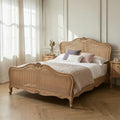 Homecrest Ancaster hand-carved natural mango wood bed with rattan detailing in a bright, elegant bedroom setting.