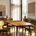 Homecrest Anders mid-century teak dining table with curved edges in a sunlit dining room with green upholstered chairs