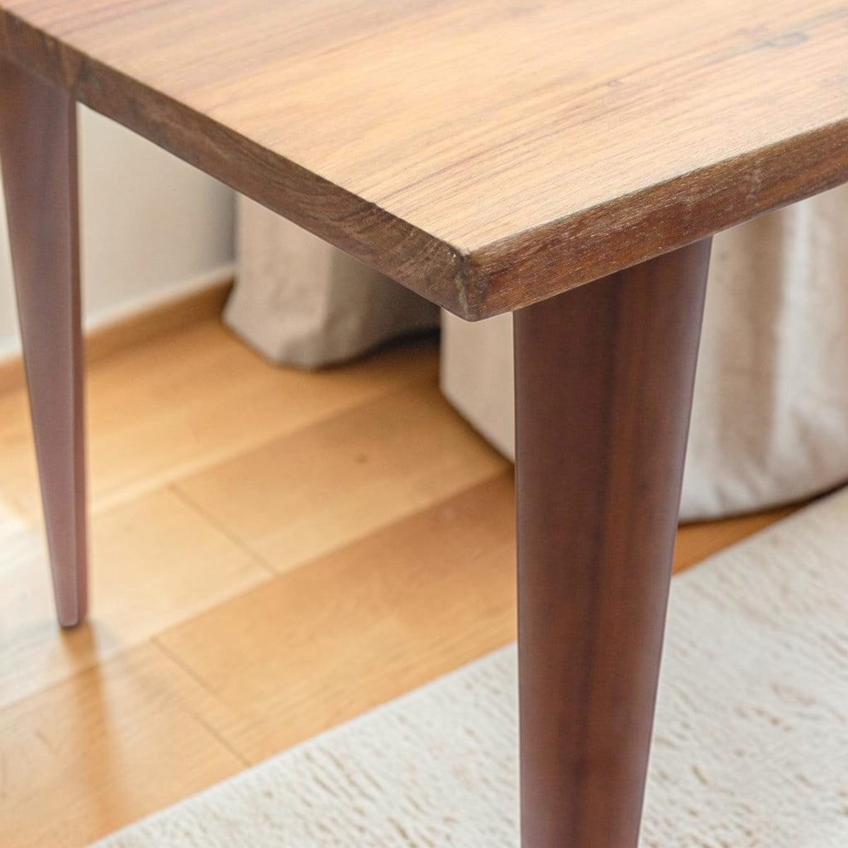 Homecrest Anders dining table in seasoned teak wood featuring a mid-century tapered leg and curved edge detail.