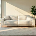 Homecrest Avebury three-seater sofa in off-white poly linen fabric with two matching throw pillows in a sunlit room.