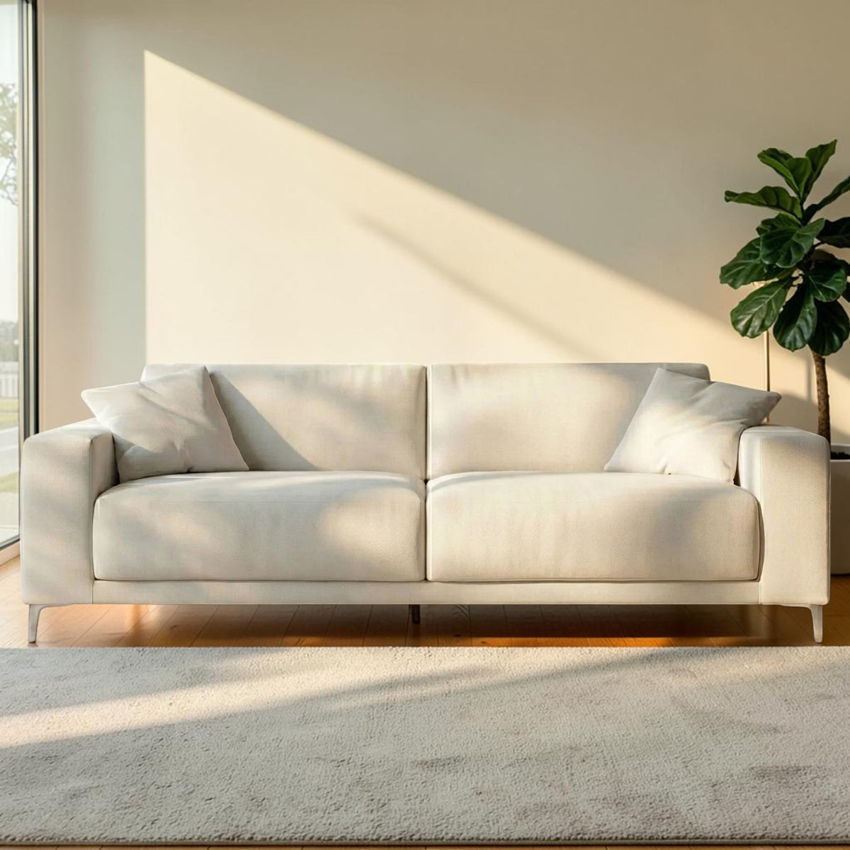 Homecrest Avebury three-seater sofa in off-white poly linen fabric with two matching throw pillows in a sunlit room.