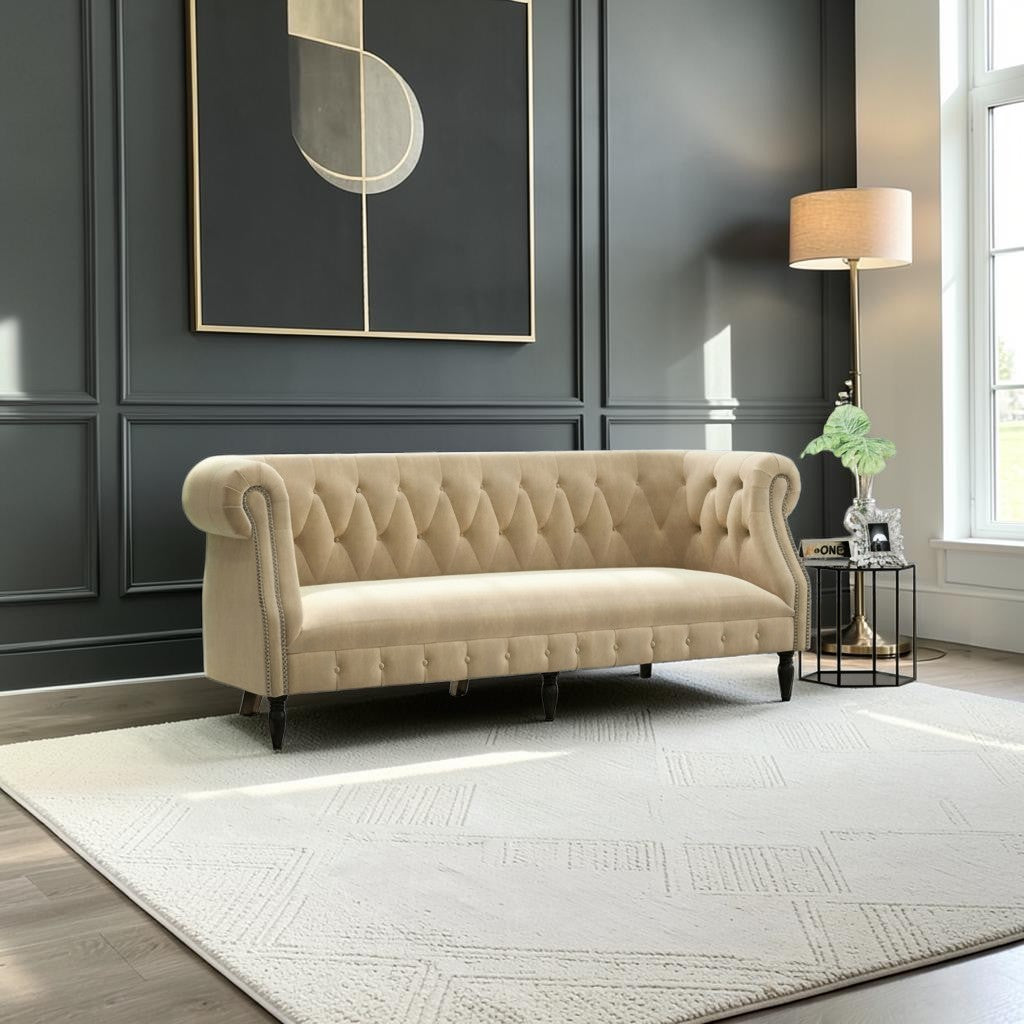 Homecrest Baslow Chesterfield sofa in beige velvet with tufted backrest and nailhead trim in a modern living room.