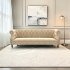 Homecrest Baslow Chesterfield sofa in beige velvet with tufted backrest and silver nailhead trim in a living room.