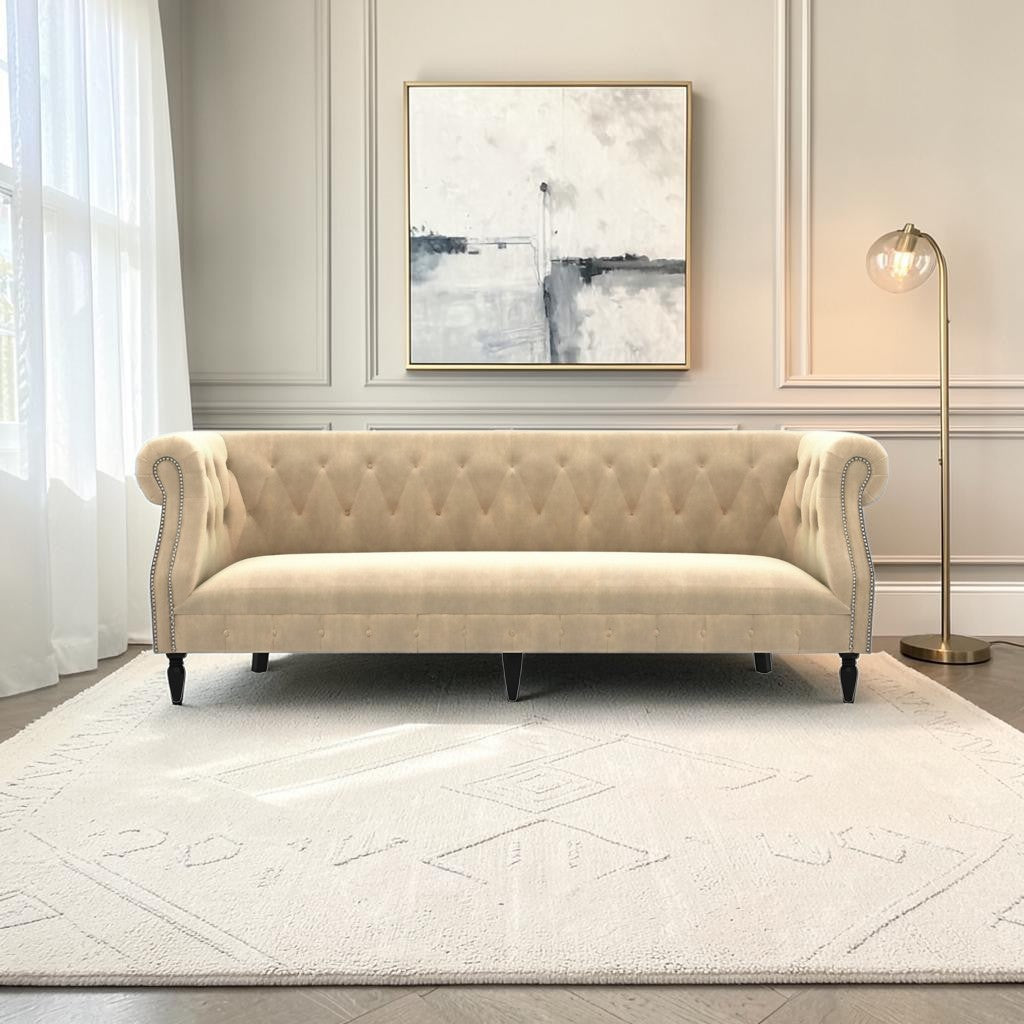 Homecrest Baslow Chesterfield sofa in beige velvet with tufted backrest and silver nailhead trim in a living room.