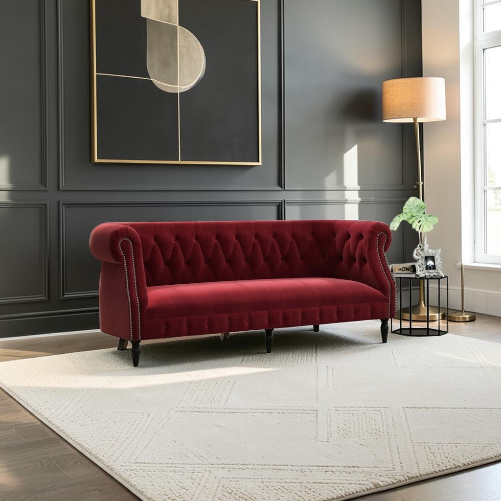 Homecrest Baslow Chesterfield sofa in pomegranate red velvet with tufted backrest and nailhead trim in a living room.