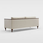Homecrest Beaumont modern classic sofa in cream fabric with dark wood turned legs and a crisp ply-and-veneer arm wrap.