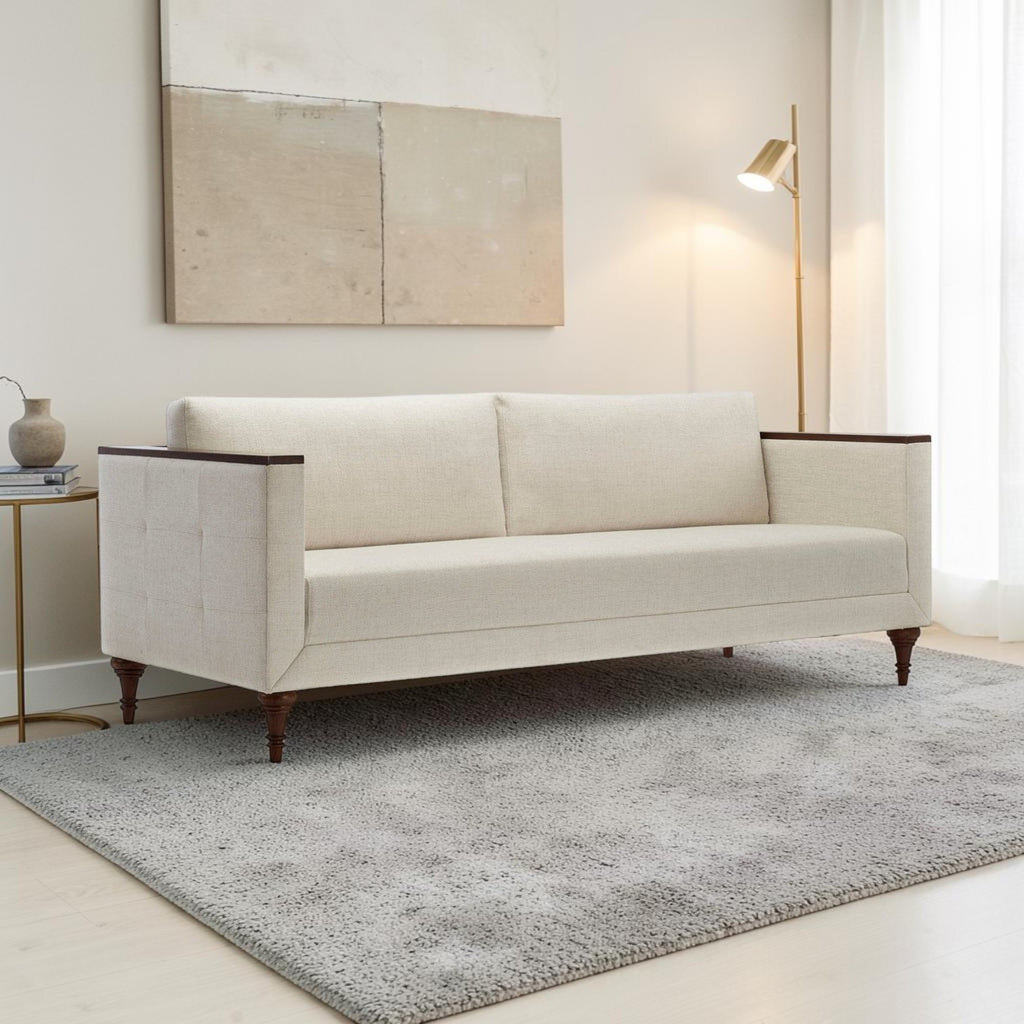 Homecrest Beaumont modern sofa in ivory fabric with dark wood arm wraps and turned teak legs in a living room.