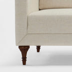 Homecrest Beaumont modern sofa featuring a cream fabric upholstery and dark stained turned teakwood legs.