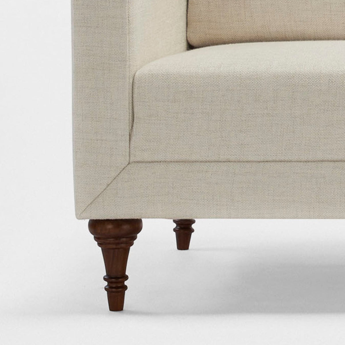 Homecrest Beaumont modern sofa featuring a cream fabric upholstery and dark stained turned teakwood legs.