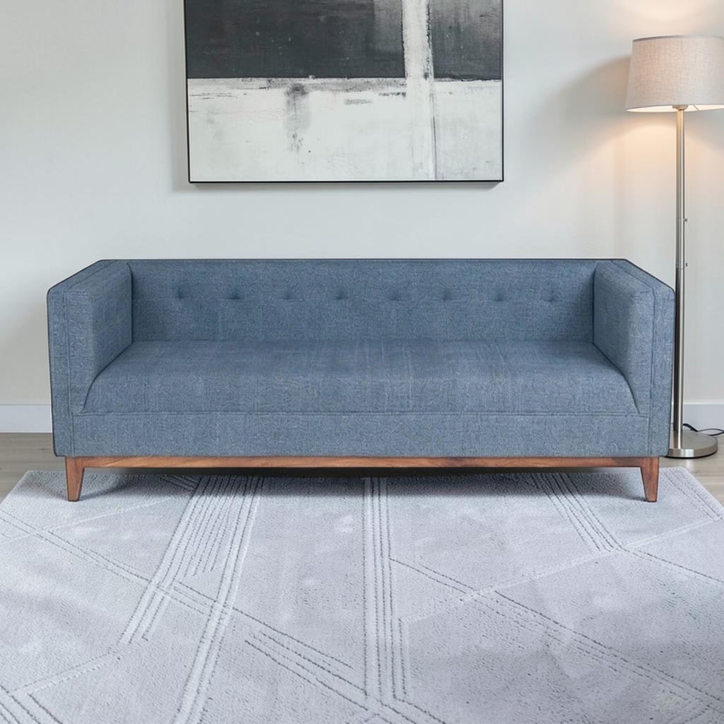 Homecrest 3-seater sofa in blue fabric with a tufted back, box arms, and a natural solid wood base in a living room.