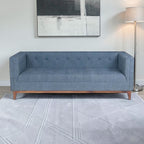Homecrest 3-seater sofa in blue fabric with a tufted back, box arms, and a natural solid wood base in a living room.
