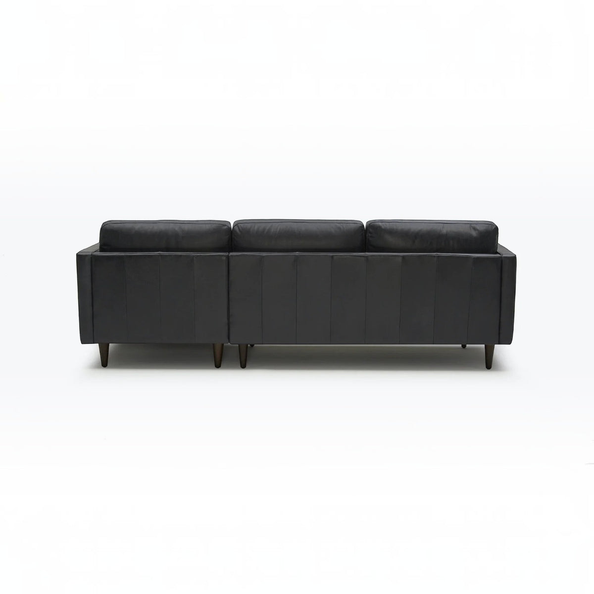 Homecrest Camber sectional sofa in rhino black leather with a deep boxy silhouette and dark wooden legs, back view.