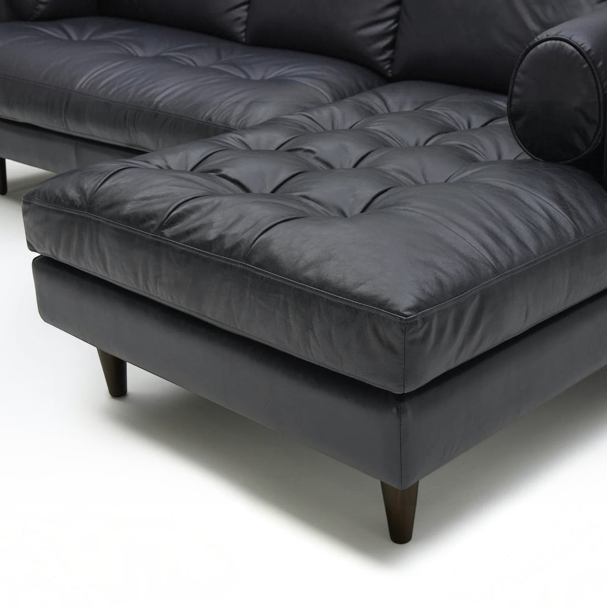 Homecrest Camber sectional sofa in rhino black leather with button-tufted seating and solid wood legs.