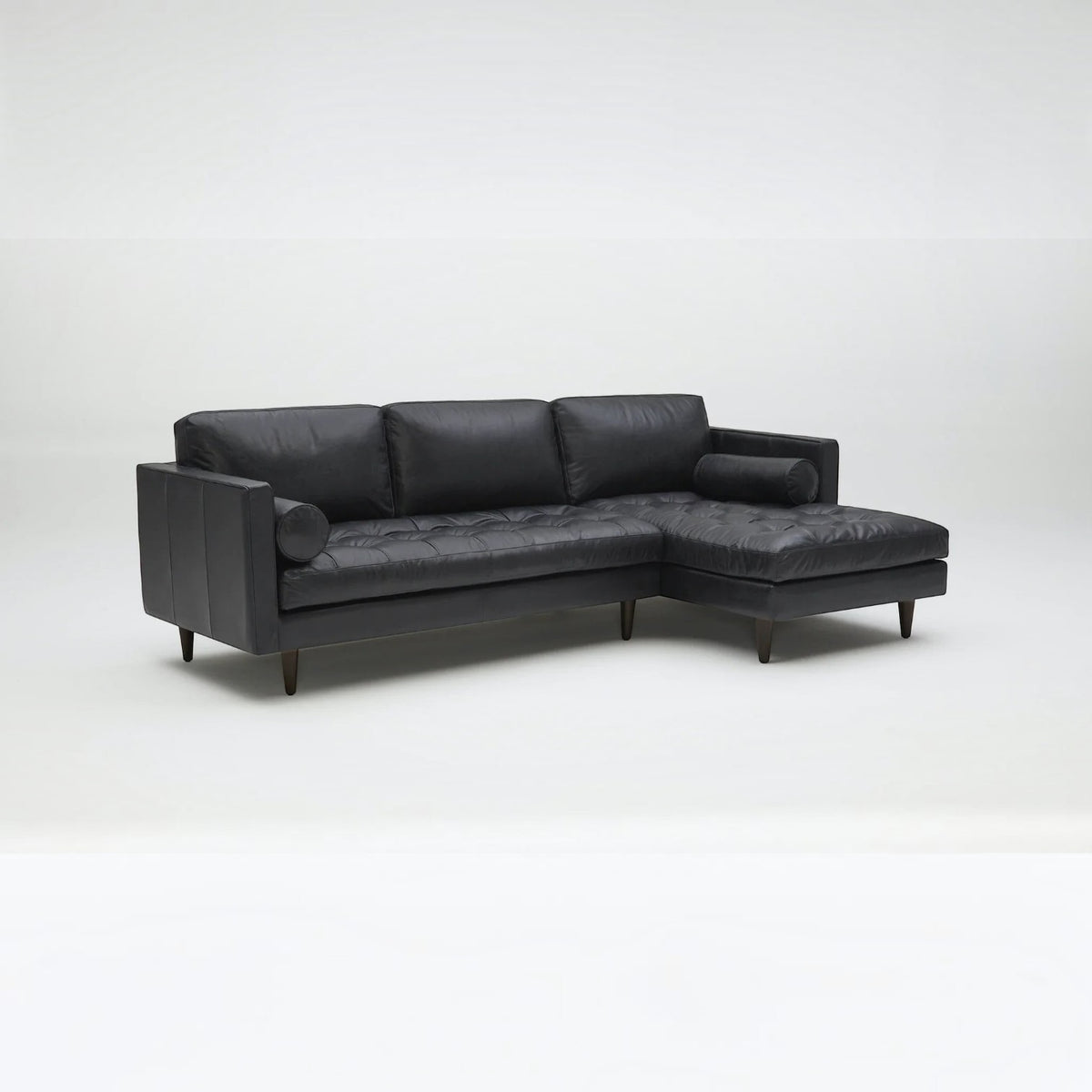 Homecrest Camber sectional sofa in rhino black leather with button-tufted seating and a deep boxy silhouette.