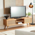 Homecrest Calder media cabinet in natural mango wood with rattan doors, gold handles, and open central shelving.