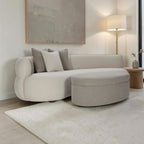 Homecrest Calla curved bean-shaped sofa in two-tone boucle fabric with matching ottoman and teakwood legs in a living room.