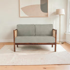Homecrest 2-seater sofa with a solid walnut wood frame, natural cane side panels, and sage green fabric cushions.