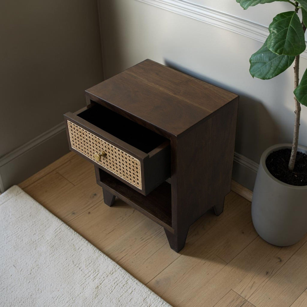 Homecrest Chalford bedside table in dark hardwood with a cane rattan drawer front and brass knob in a bedroom setting.