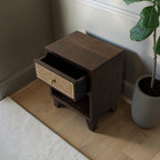 Homecrest Chalford bedside table in dark hardwood with a cane rattan drawer front and brass knob in a bedroom setting.