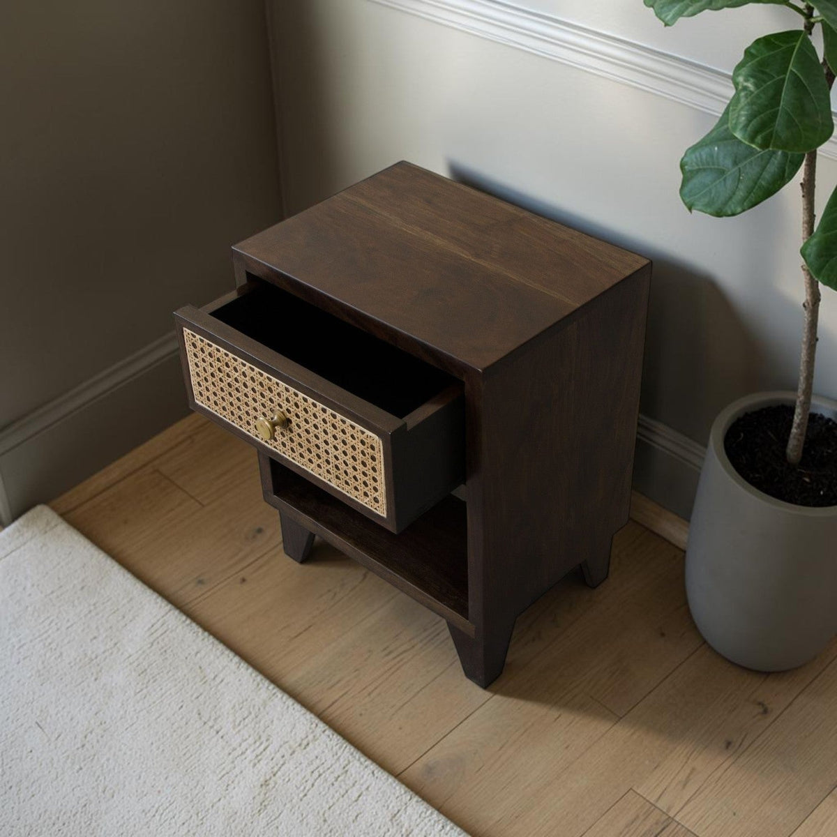 Homecrest Chalford bedside table in dark hardwood with a cane rattan drawer front and brass knob in a bedroom setting.