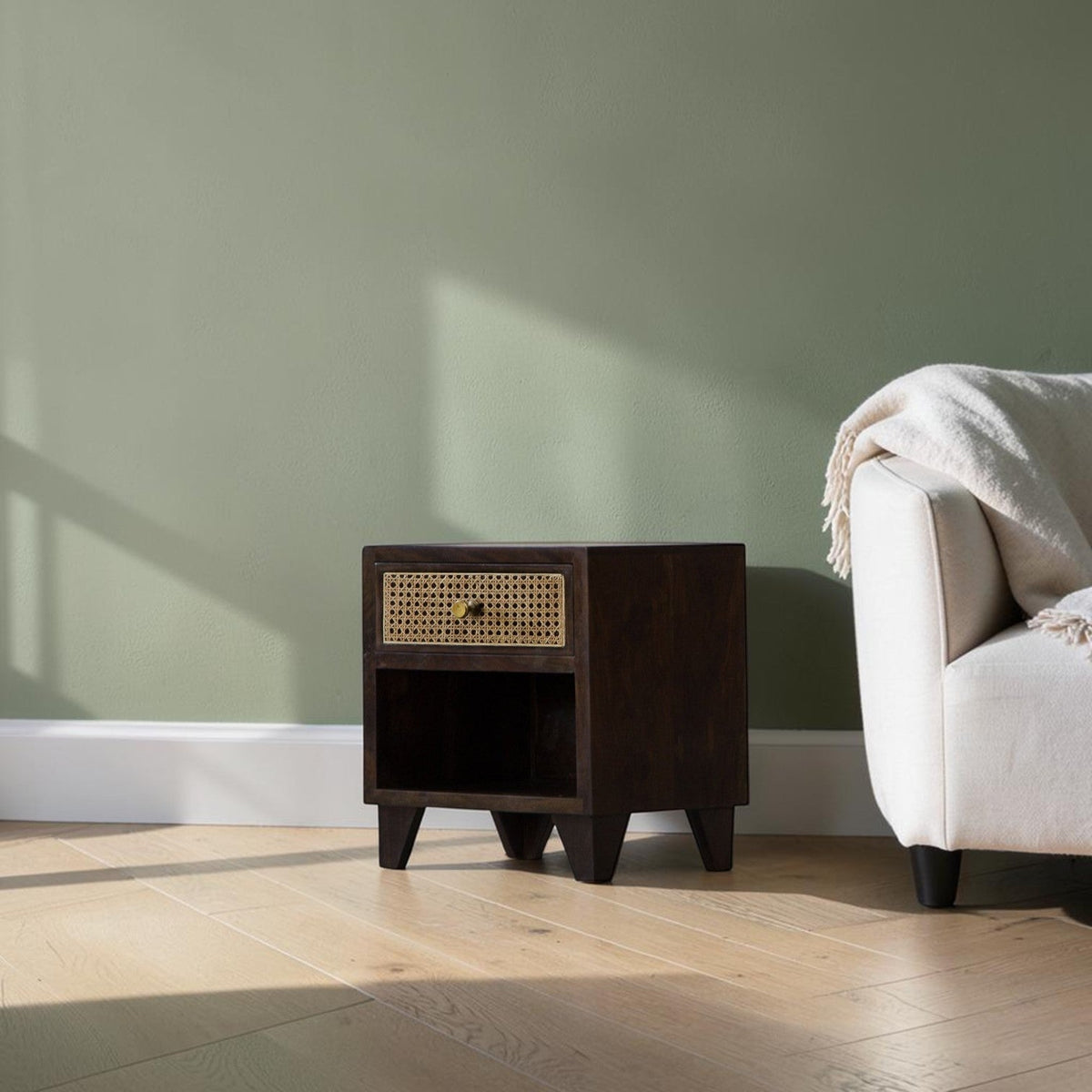 Homecrest Chalford bedside table in dark hardwood with a cane rattan drawer front and brass knob in a living room.