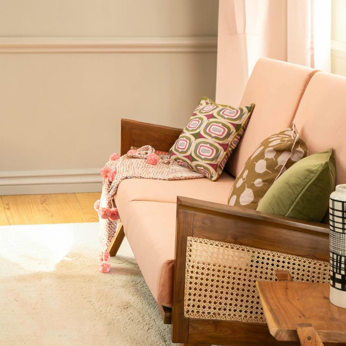 Homecrest Culworth mid-century slim teak wood sofa with light pink upholstery and cane side panels in a bright room