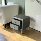 Homecrest Cranham bedside table in a dark grey finish with two drawers and silver knobs on a wooden floor.