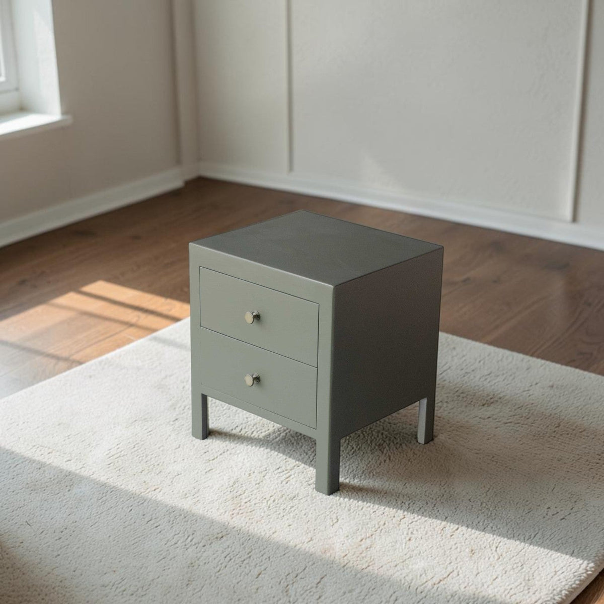 Homecrest Cranham bedside table in sage green hardwood with two drawers and minimalist silver knobs on a rug.