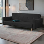 Homecrest Corbett black leatherette three-seater sofa bed with tufted detailing and solid wood frame in a modern room.
