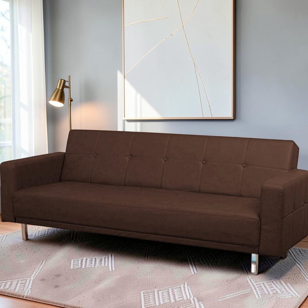 Homecrest Corbett brown leatherette three-seater sofa bed with tufted backrest and modern metal legs in a living room.