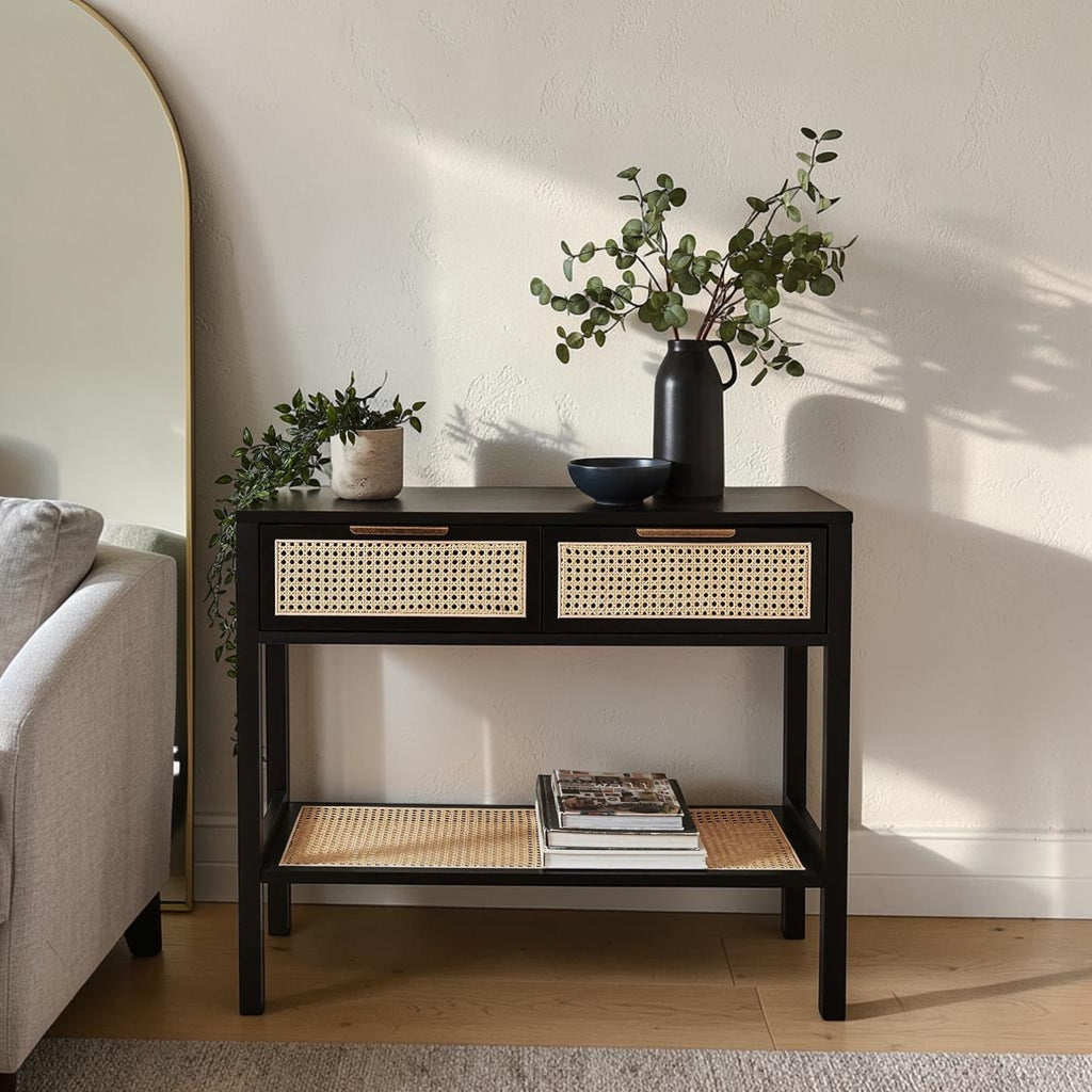 Homecrest Corvin black mango wood console table with two rattan cane doors and a lower storage shelf in a living room
