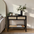Homecrest Corvin black mango wood console table with two rattan cane doors and a lower storage shelf in a living room