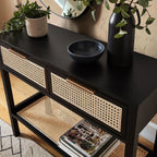 Homecrest Corvin black mango wood console table with two rattan cane doors and a lower shelf in a modern hallway