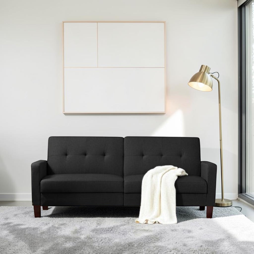 Homecrest Delaney black three-seater sofa bed with tufted backrest and solid wood legs in a modern living room.