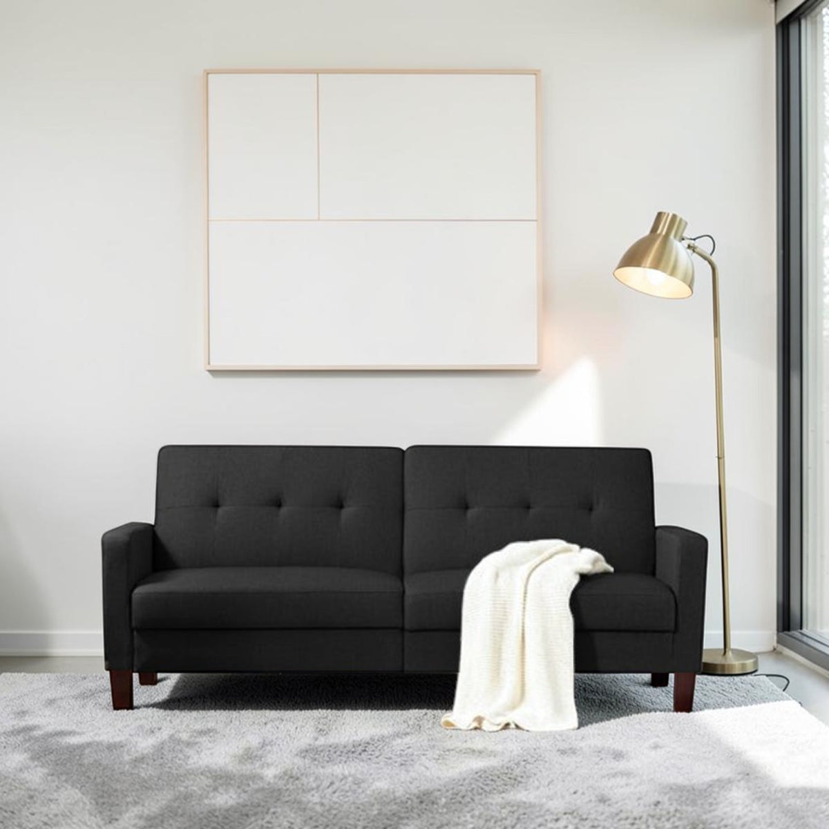 Homecrest Delaney black three-seater sofa bed with tufted backrest and solid wood legs in a modern living room.