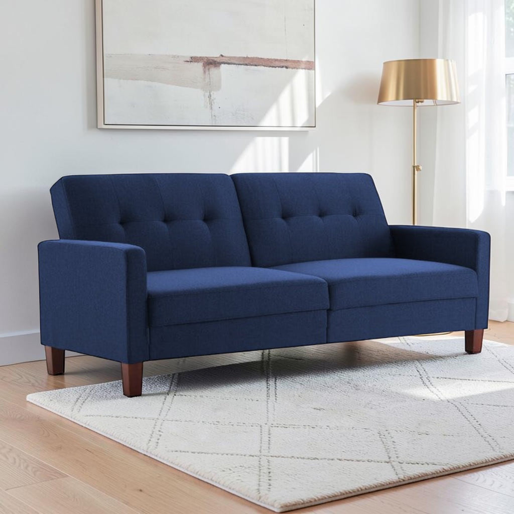 Homecrest Delaney navy blue three-seater sofa bed with tufted back cushions and solid wood legs in a bright room.