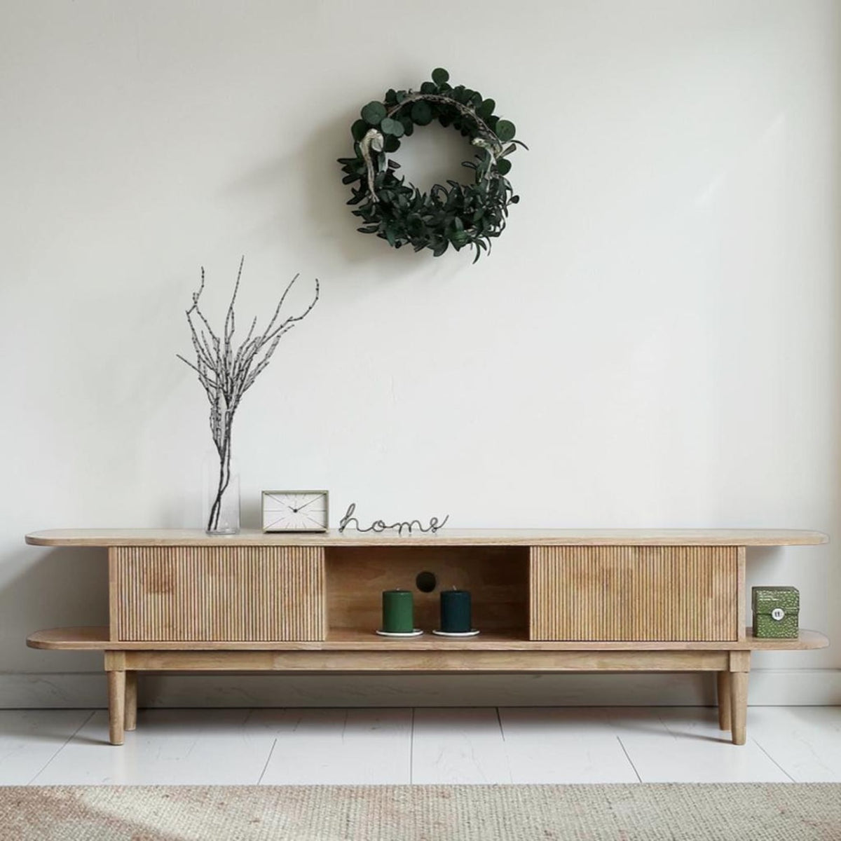 Homecrest Fallow media cabinet in natural mango wood with a fluted sliding door and open shelving.