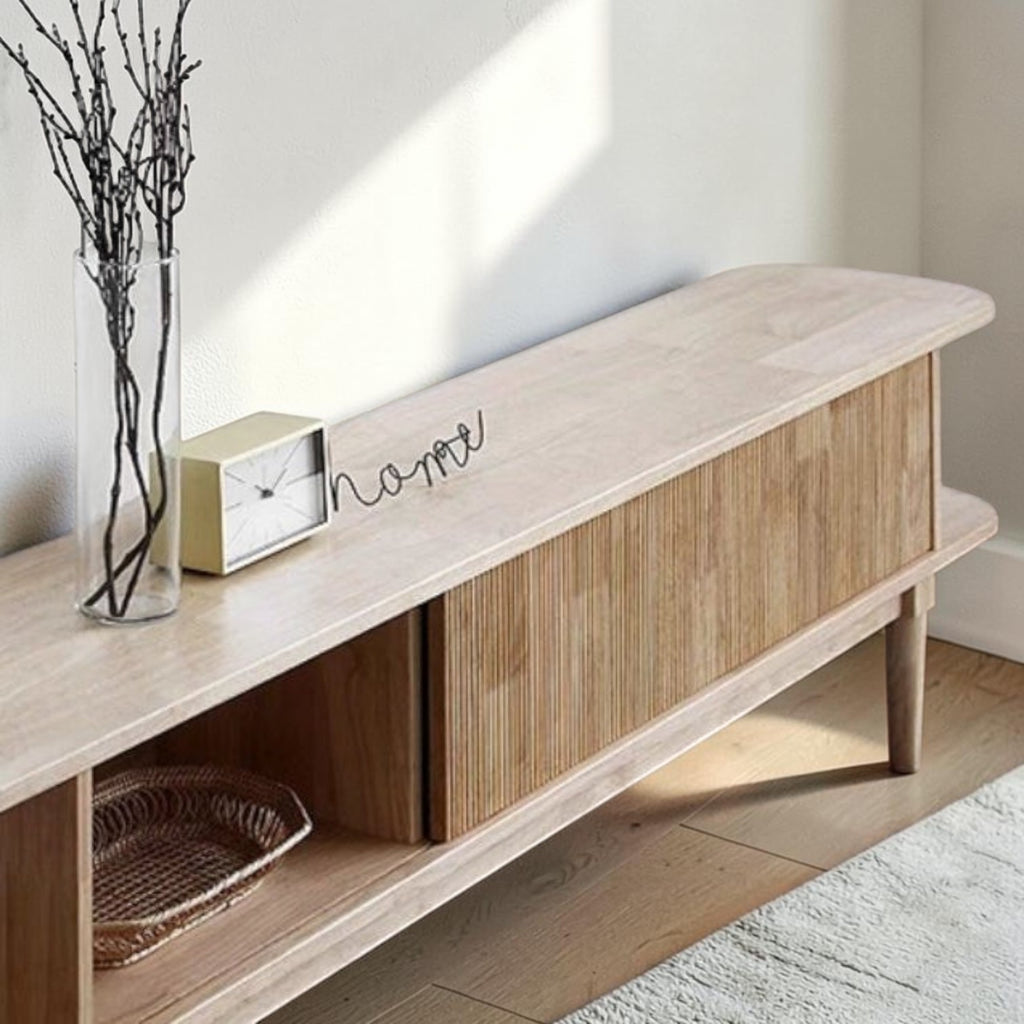Homecrest Fallow media cabinet in natural mango wood with a fluted sliding door and minimalist tabletop decor.