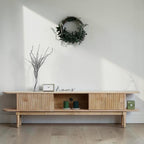 Homecrest Fallow media cabinet in natural mango wood with fluted sliding doors and open central shelving.