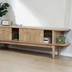Homecrest Fallow media cabinet in natural mango wood with a fluted sliding door and open shelving.