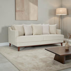 Homecrest Halden mid-century modern sofa in cream fabric with tapered teak wood legs in a minimalist living room.