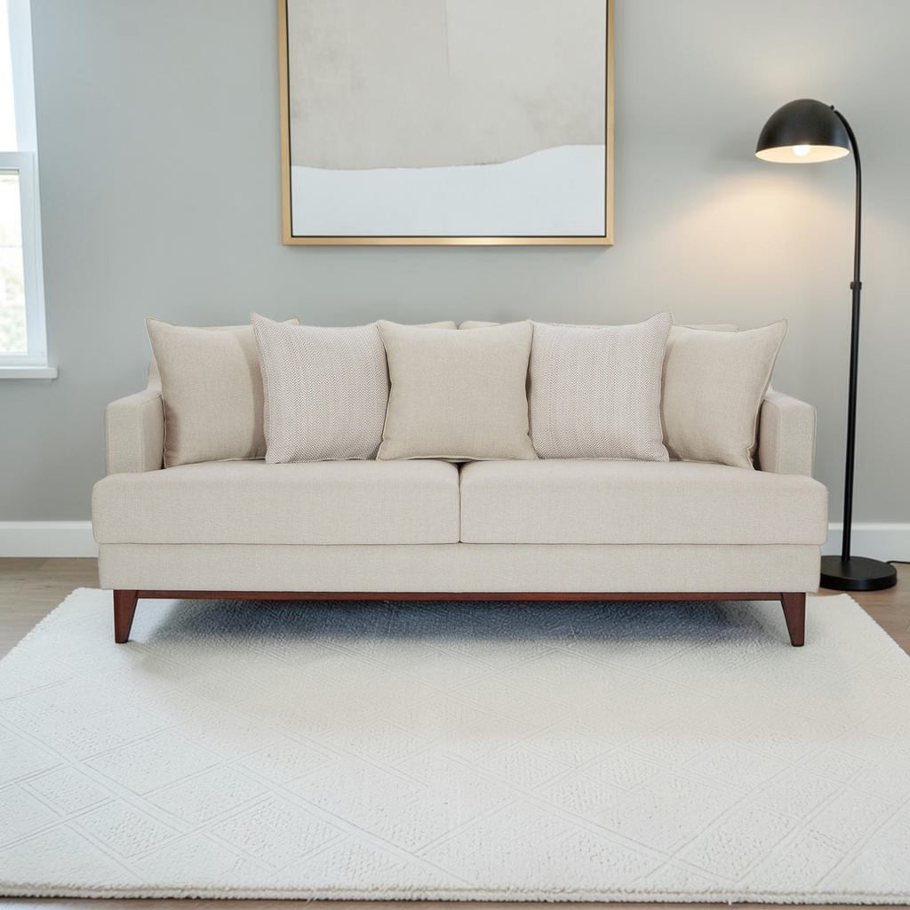 Homecrest Halden mid-century modern sofa in beige fabric with tapered teak wood legs in a minimalist living room.