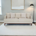 Homecrest Halden mid-century modern sofa in beige fabric with tapered teak wood legs in a minimalist living room.