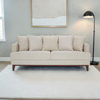Homecrest Halden mid-century modern sofa in beige fabric with tapered teak wood legs in a minimalist living room.