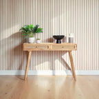 Homecrest Isla natural wood console table with two woven rattan cane drawers and gold handles against a slat wall