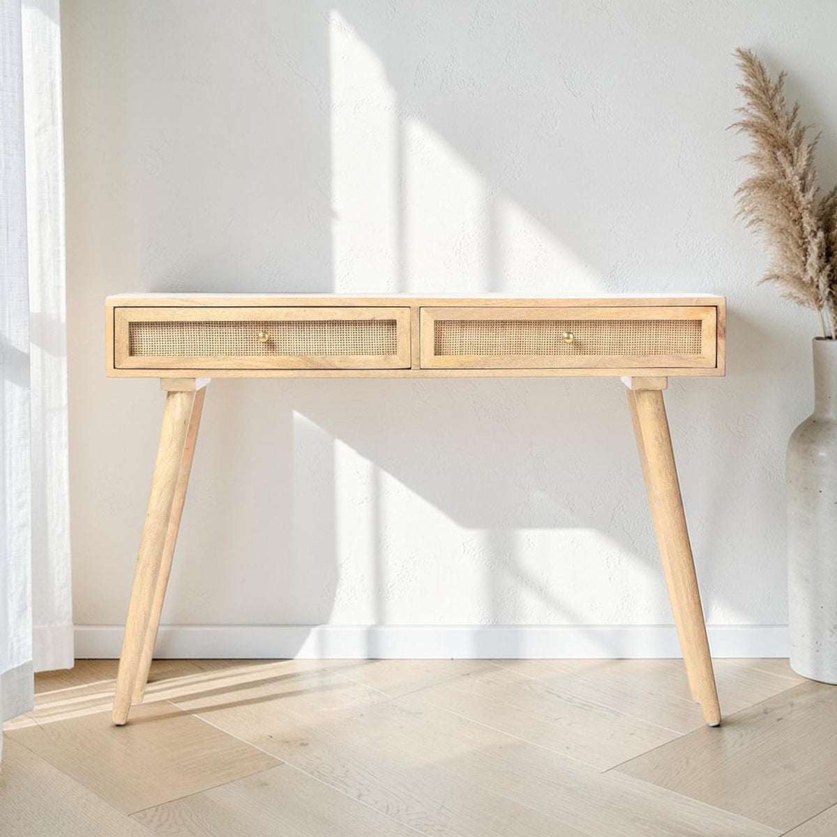Homecrest Isla natural wood console table with two woven rattan cane drawers and gold handles in a bright hallway.