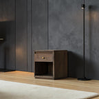 Homecrest Latimer bedside table in dark antiqued wood with a single drawer and open shelf against a dark wall.